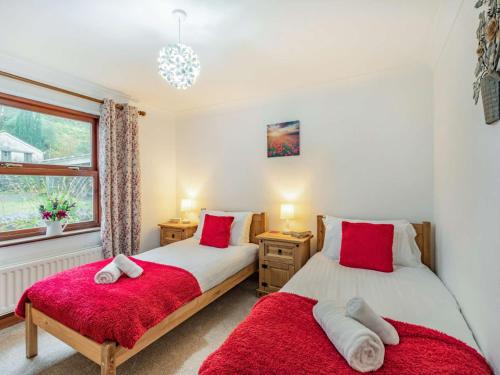 two beds in a bedroom with red pillows at 2 Bed in Borrowdale 86397 in Rosthwaite