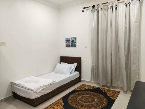 a bed in a room with a curtain and a rug at Cwa Homestay in Kampong Molek