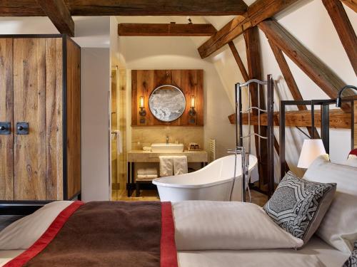 a bedroom with a bed and a bathroom with a tub at PEST-BUDA Design Hotel by Zsidai Hotels at Buda Castle in Budapest