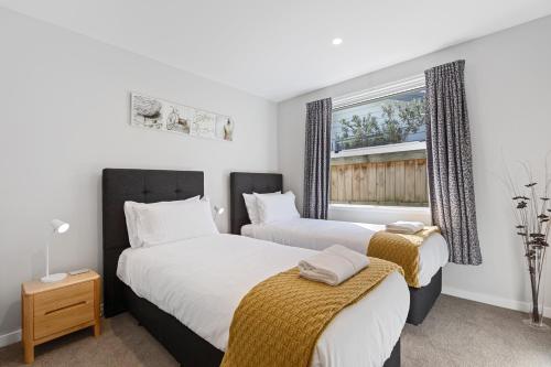 two beds in a room with a window at Papamoa Beach Retreat in Tauranga