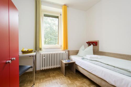 波昂的住宿－波恩青年旅館，一间卧室配有一张床、一张书桌和一个窗户。
