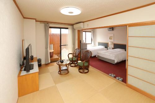 a room with a bedroom with a bed and a tv at Hotel Sunresort Shirahama in Shirahama