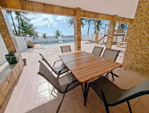 a wooden table and chairs on a patio with a pool at Blue house on blue beach in Pitimbú PB in Pitimbu