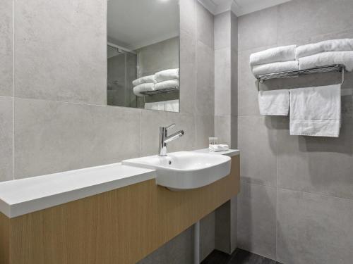une salle de bain avec un lavabo, un miroir et des serviettes dans l'établissement ibis Styles Canberra Eagle Hawk, à Canberra