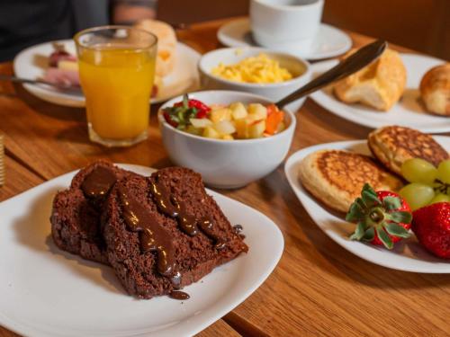 a wooden table topped with plates of food and drinks at Ibis Guaratingueta Aparecida - Circuito da Fé in Guaratinguetá