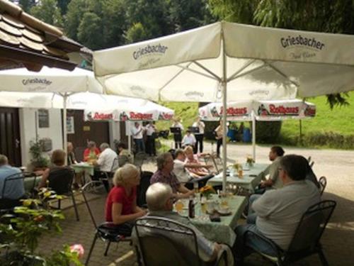 a group of people sitting at tables under umbrellas at Landgasthaus zum Engel in Freiamt