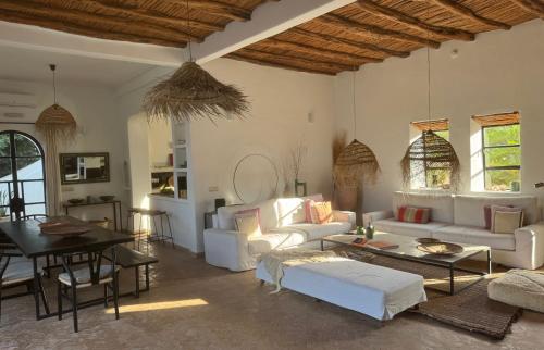 a living room with white furniture and a table at Palais Bleu Nomade Essaouira in Aït Imouni