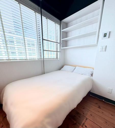 a large white bed in a room with windows at GARDEN HOUSE Tameike-Sanno in Tokyo
