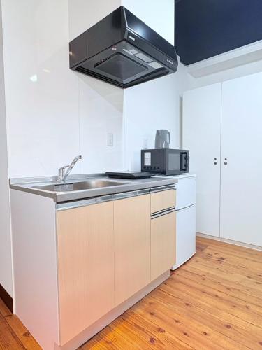 a white kitchen with a sink and a microwave at GARDEN HOUSE Tameike-Sanno in Tokyo