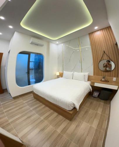 a bedroom with a large white bed and a window at Ami Hoi An Home in Hoi An