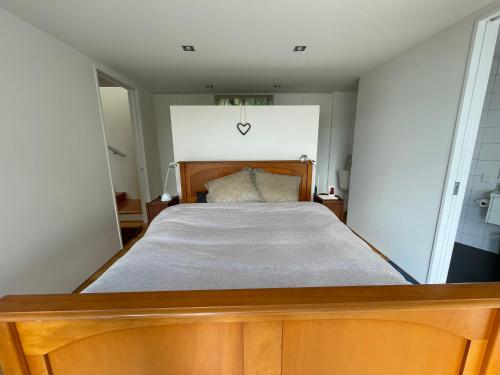 a bedroom with a wooden bed in a room at Hosts on the Coast Paku Paradise in Tairua