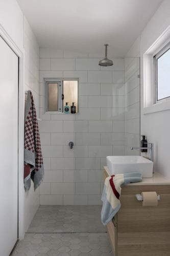 a white bathroom with a sink and a shower at The Local House - Byron Bay in Byron Bay
