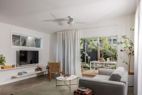 a living room with a couch and a tv at The Local House - Byron Bay in Byron Bay