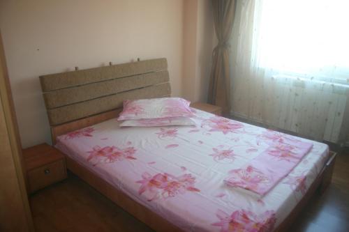 マンガリアにあるApartament Anthonyのベッドルーム1室(ピンクの花が咲くベッド1台付)