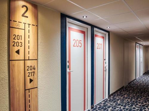 a hallway with doors and numbers on the wall at Hôtel Ibis Budget Nantes Ouest Atlantis Couëron in Couëron