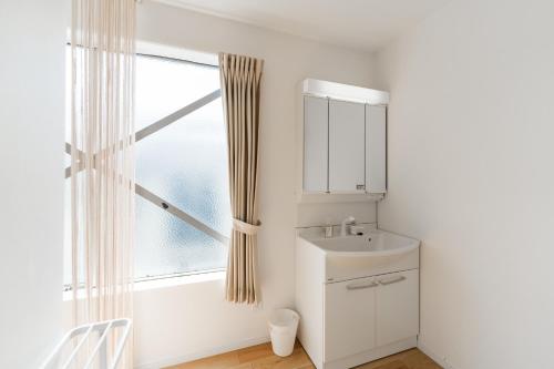 une salle de bain blanche avec un lavabo et une fenêtre dans l'établissement Flower Base Lily House - Vacation STAY 55464v, à Fukuoka
