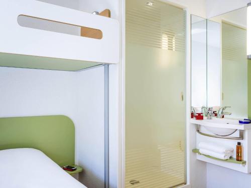 a small bedroom with a bed and a mirror at ibis budget Issy Les Moulineaux Paris Ouest in Issy-les-Moulineaux