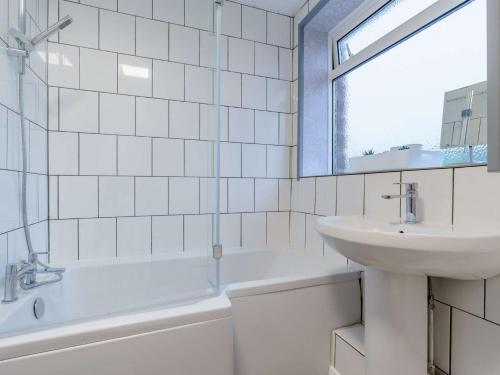 a white tiled bathroom with a sink and a bath tub at 4 Bed in Gosforth 85807 in Gosforth