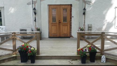 a porch with two potted plants and a wooden door at Bjärkeryd Södergård Bed & Stable in Kisa