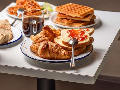 シャポネにあるibis budget Lyon Est Chaponnayのパン、ワッフル、パンケーキの皿が置かれたテーブル