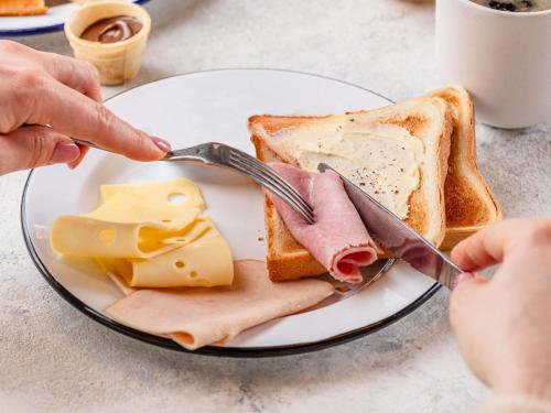 シャポネにあるibis budget Lyon Est Chaponnayのパンとチーズを乗せた料理を食べている人