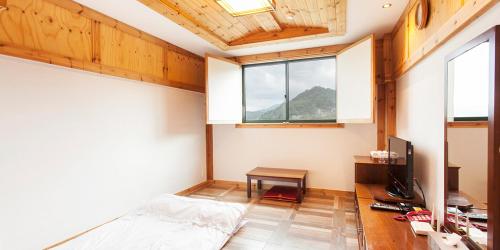 a bedroom with a bed and a desk and a window at Benikea Hotel Cheong Do Hot Spring in Cheongdo