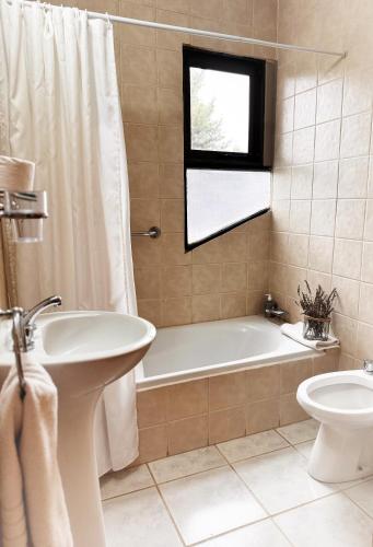 a bathroom with a tub and a toilet and a sink at Hosteria Andina in Esquel