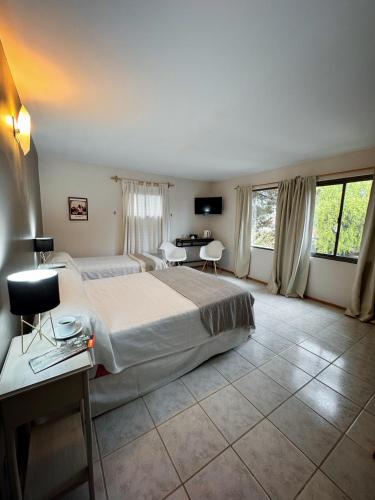 a hotel room with a large bed and a table at Hosteria Andina in Esquel