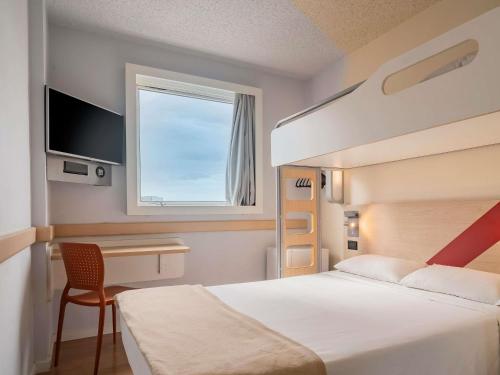 Un dormitorio con una cama y un escritorio y una ventana. en ibis budget Sao Paulo Paulista, en São Paulo