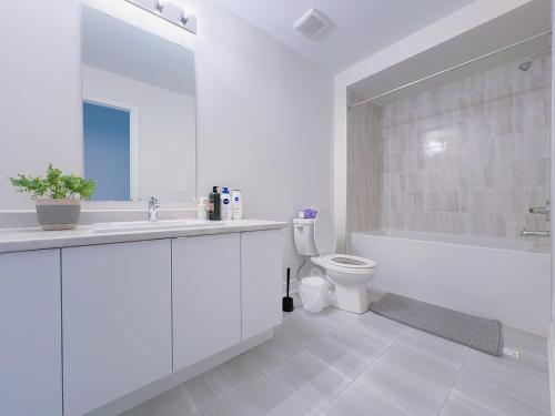 a white bathroom with a sink and a toilet at Vantage stay Modern 4BR townhouse pickering in Pickering