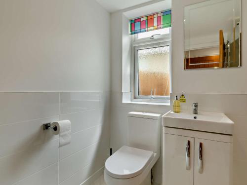a bathroom with a toilet and a sink and a window at 2 Bed in Barnstaple 94038 in Bishops Tawton
