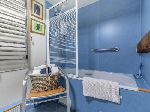 a blue bathroom with a tub and a basket on a stool at 2 Bed in Bewdley CC090 in Bayton