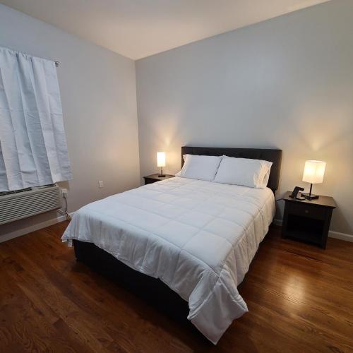 a bedroom with a large white bed with two lamps at Spacious Apt in Fairview NJ Easy Commute to NYC with parking in Fairview