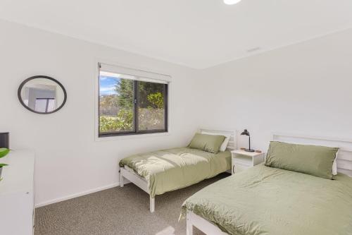 Dos camas en una habitación blanca con ventana. en 9 Callow Place, en Bermagui