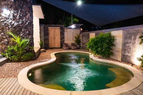 a swimming pool in a backyard at night at Villa D'Ling in Tianyar