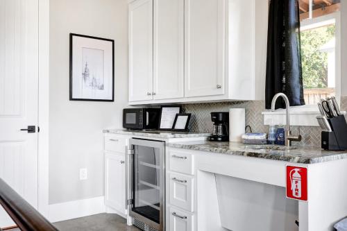 a white kitchen with white cabinets and a microwave at Blanco - A Birdy Vacation Rental in Fredericksburg