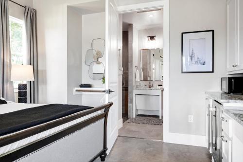 a white bedroom with a bed and a bathroom at Blanco - A Birdy Vacation Rental in Fredericksburg
