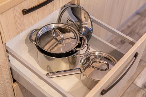 ティミショアラにあるMara Luxury Golden Art, Apartment PLUS Free Parkingのキャビネットの棚にたくさんの鍋やフライパンが置かれている