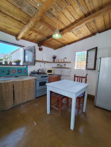 eine Küche mit einem weißen Tisch und einem Kühlschrank in der Unterkunft Casa de Altura in Tilcara