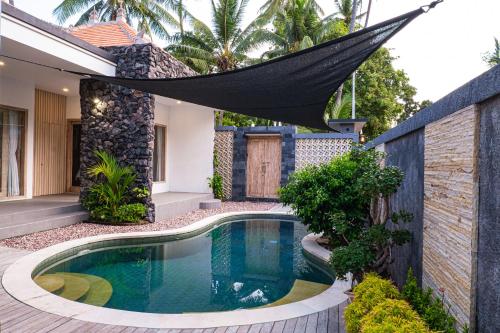 a hammock hangs over a swimming pool in a house at Villa D'Ling in Tianyar