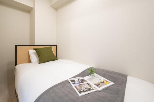 a bedroom with a bed with a book on it at Daffitto Oshiage II in Tokyo
