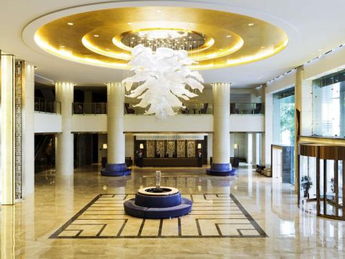 een lobby met een kroonluchter in het midden van een gebouw bij Pullman Changshu Leeman in Changshu