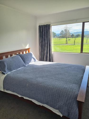 een slaapkamer met een bed en een groot raam bij The Barnyard Cottage in Otakiri