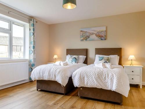 two beds in a bedroom with two lamps and a window at 4 Bed in Alsop-En-Le-Dale 88935 in Alsop en le Dale