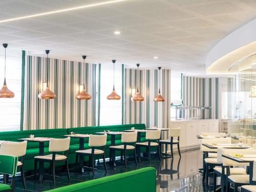 a restaurant with green and white tables and chairs at Hotel Mercure Jardines de Albia in Bilbao