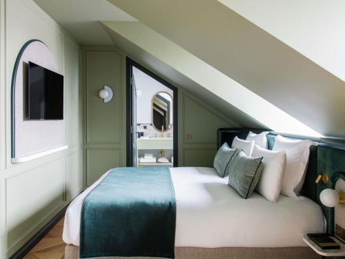 a bedroom with a large bed and two windows at l'Echiquier Opéra Hotel Paris - MGallery Collection in Paris