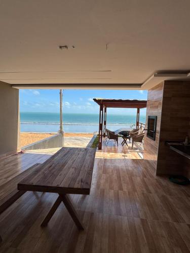 a living room with a table and a view of the beach at Casa da Maré Pé na areia Suítes climatizadas e deck vista mar in Icapuí