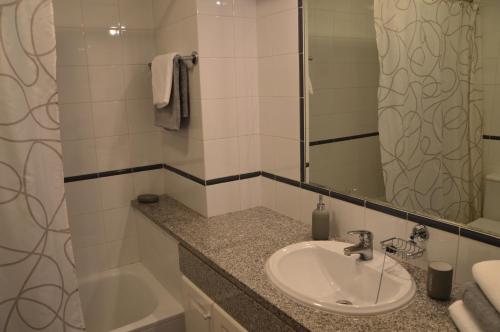 a bathroom with a sink and a mirror and a tub at Portugal Algarve Beach Apartment in Portimão
