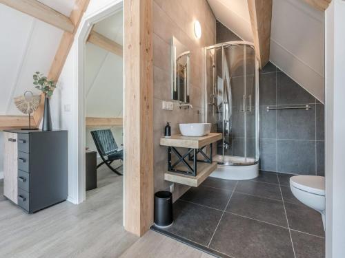 a bathroom with a shower and a sink and a toilet at Thatched bungalow with private terrace in Schaluinen