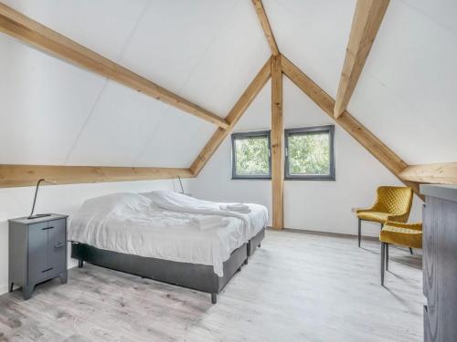 a bedroom with a bed and two chairs in a attic at Modern lodge stay with pond view in Schaluinen